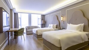 Una habitación de hotel con dos camas, un sofá, una mesa de comedor y un televisor.