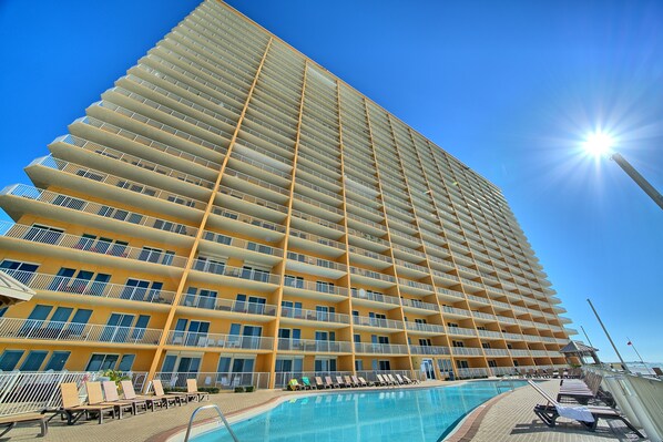 A high-rise hotel with multiple balconies, a swimming pool, and sunbathing areas. - Treasure Island 1007 (Panama City Beach)