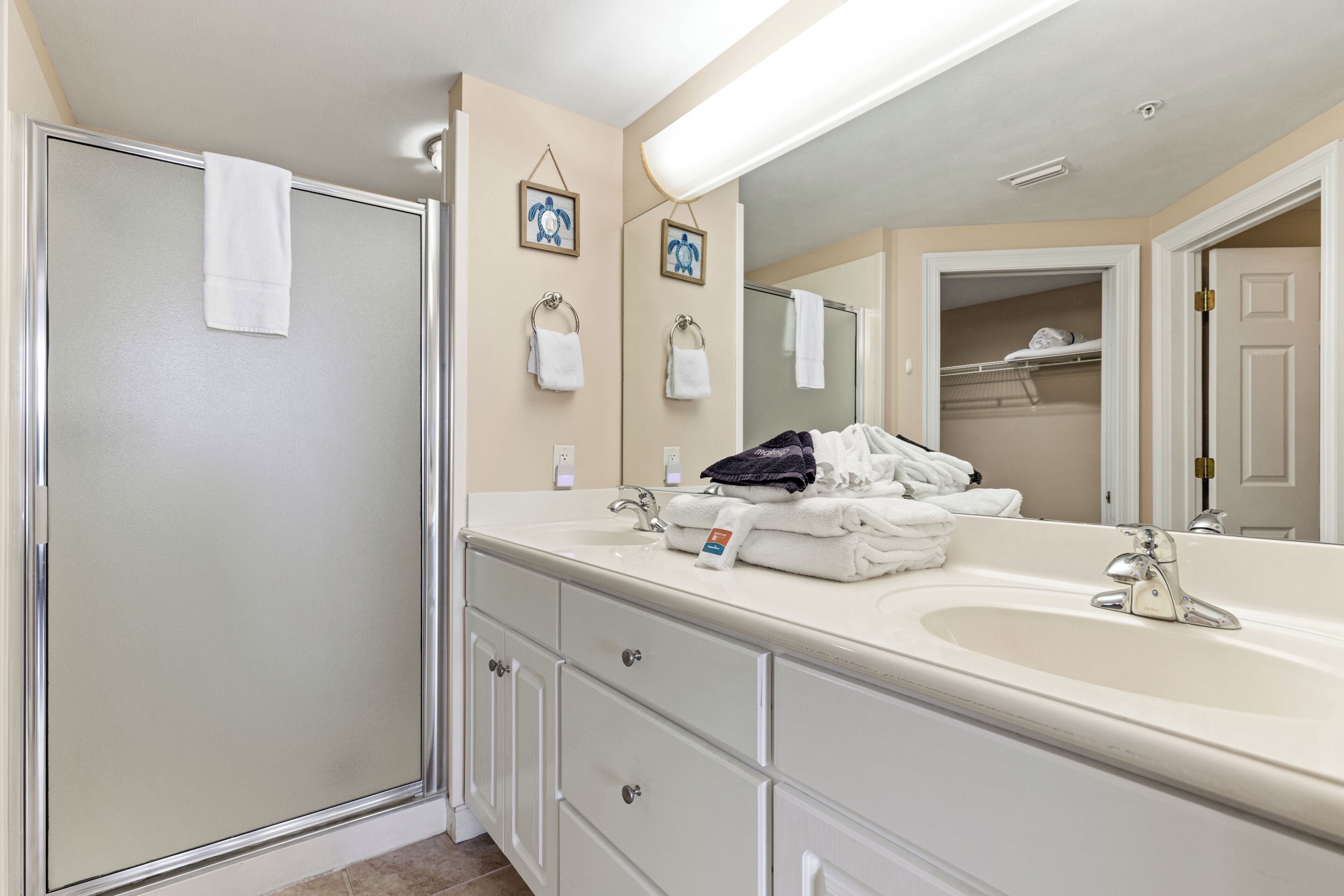 A bathroom with a shower, a sink, a mirror, and a towel rack.