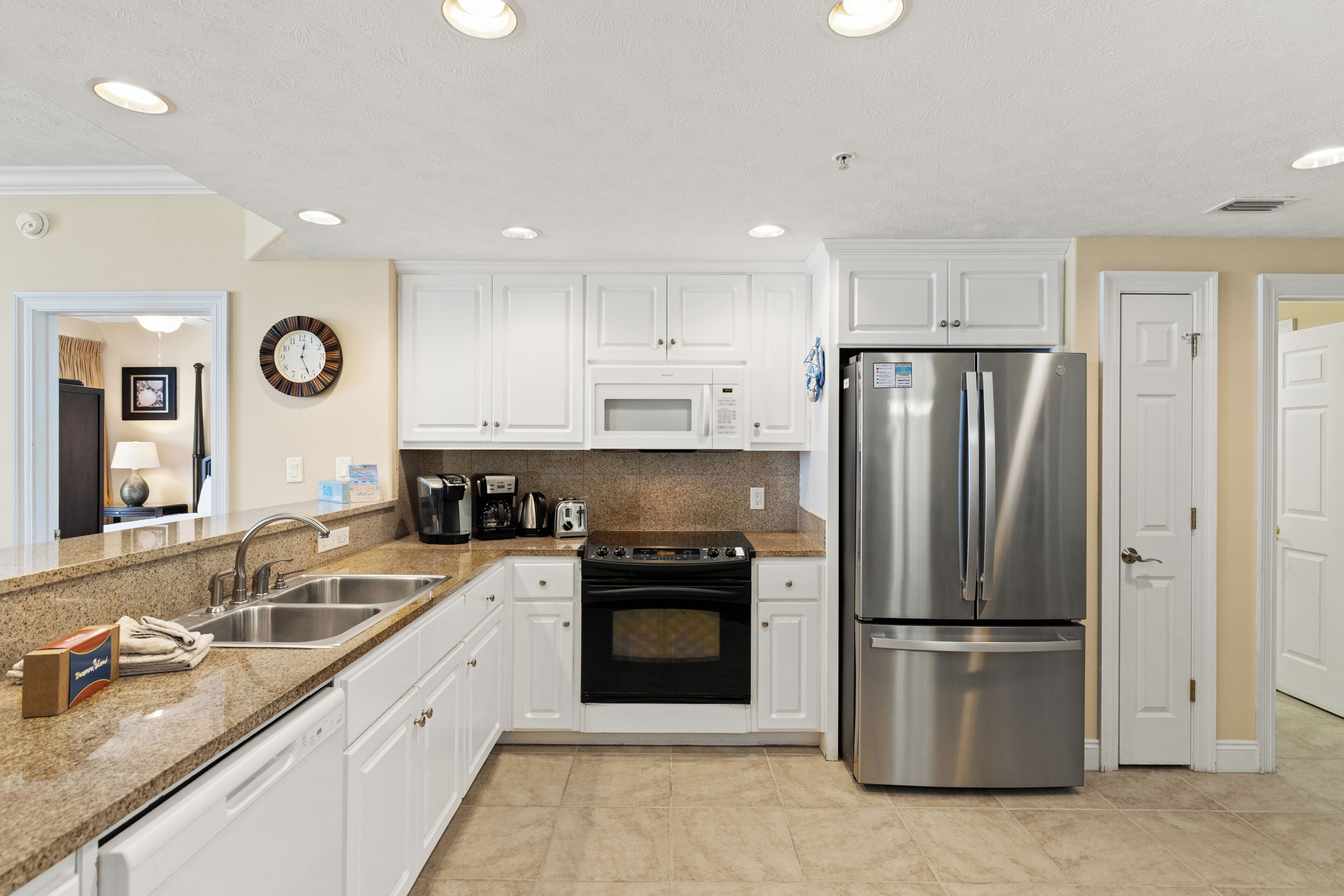 A modern kitchen with white cabinets, stainless steel appliances, and a granite countertop.