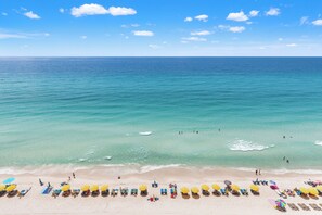 Ein Strand mit Reihen von Liegestühlen und Sonnenschirmen, bewölkter Himmel und dem Meer.