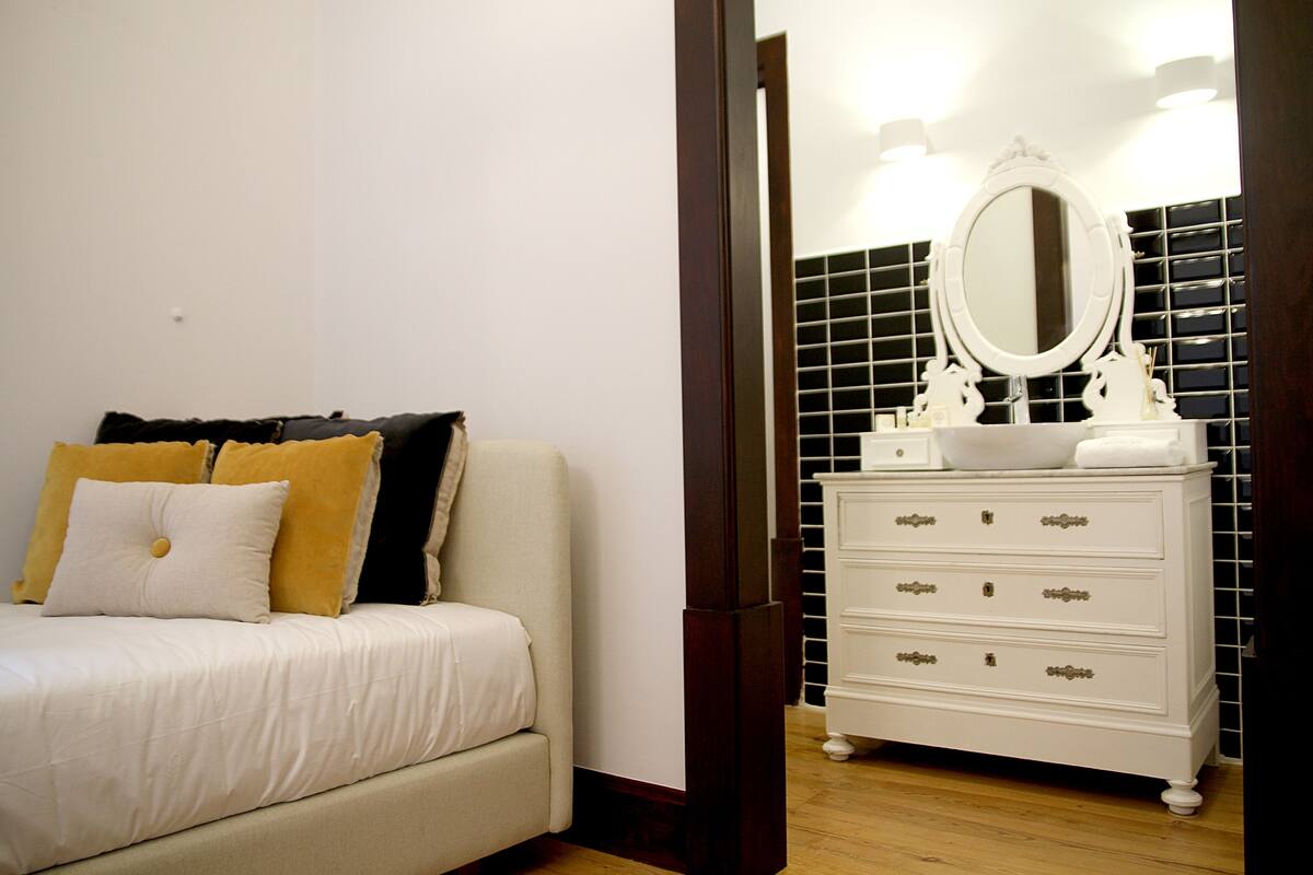 Un dormitorio con una cama, un tocador con espejo y una pared con azulejos.