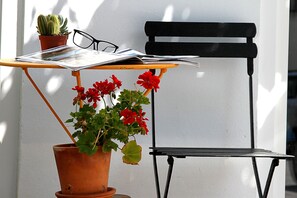 Una silla, una mesa, una planta en maceta y un par de gafas sobre la mesa.