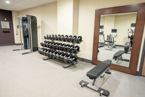 A gym with dumbbells, a bench, and exercise equipment.