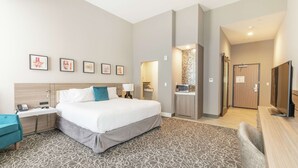 Een moderne hotelkamer met een groot bed, een bureau, een stoel, een televisie en een badkamer zichtbaar door een geopende deur.