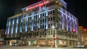 Een Hilton Garden Inn hotel met een moderne gevel, grote ramen en opvallend bewegwijzeringsbord.