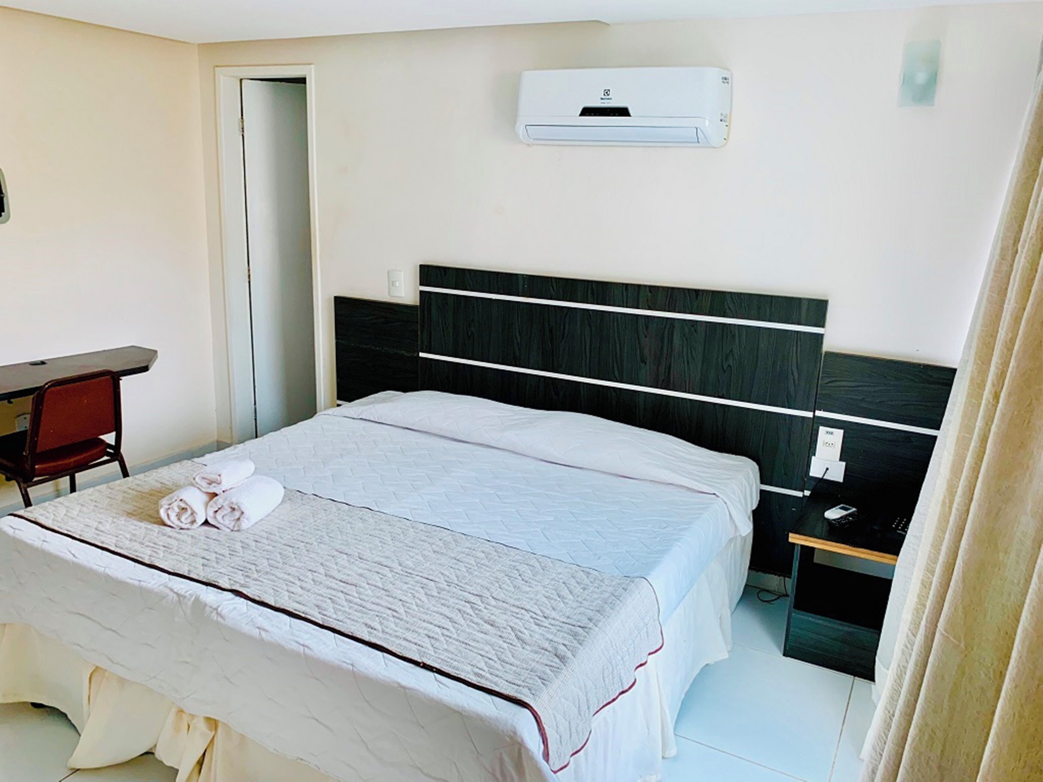 Una habitación de hotel con cama, escritorio y aire acondicionado.