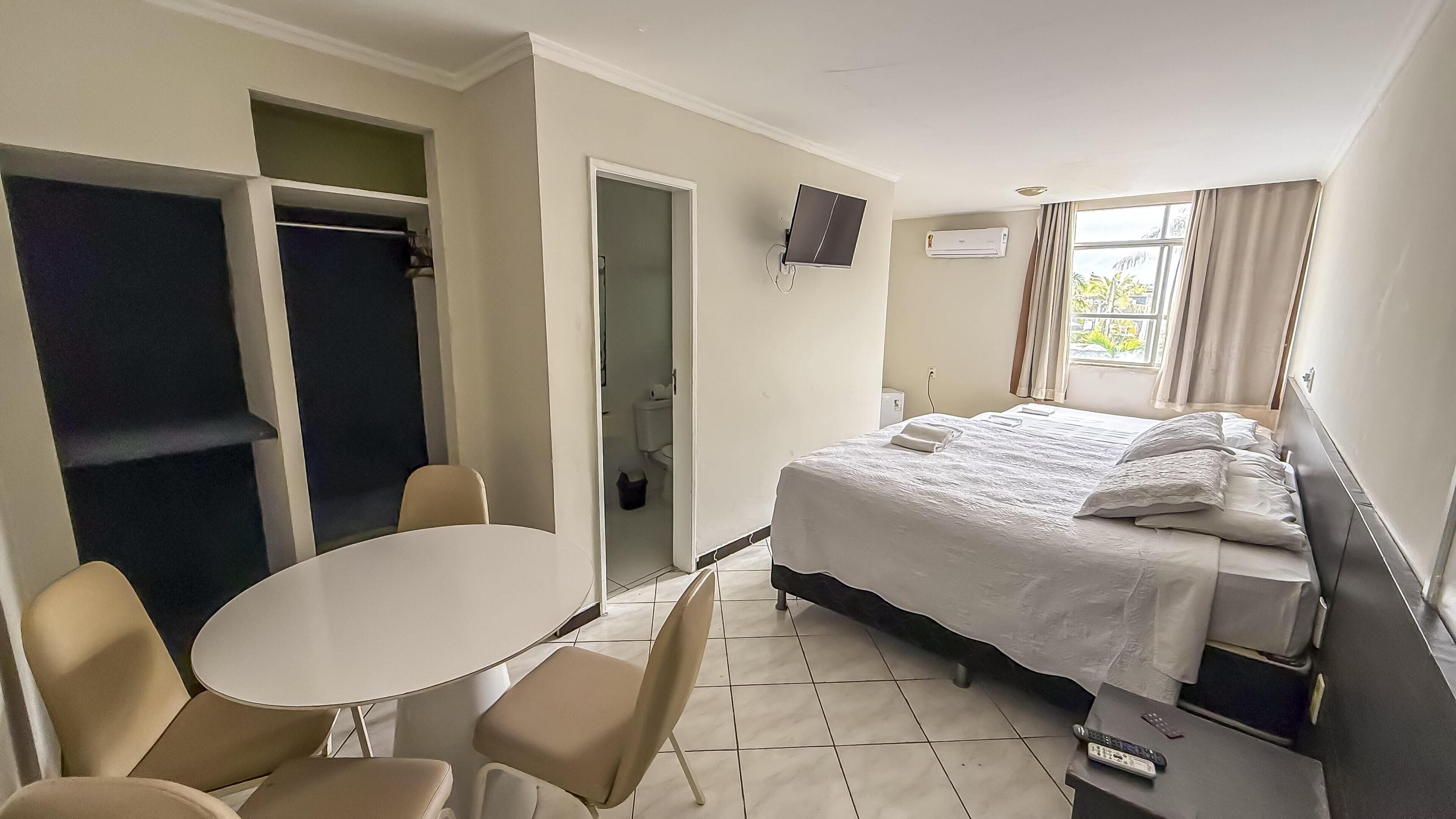 Una habitación de hotel con cama, televisión, mesa y dos sillas.