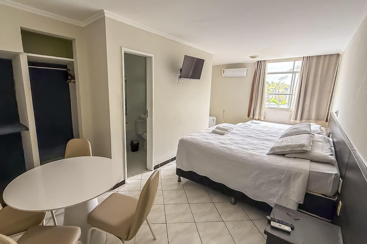 A hotel room with a bed, a TV, a table, and two chairs.