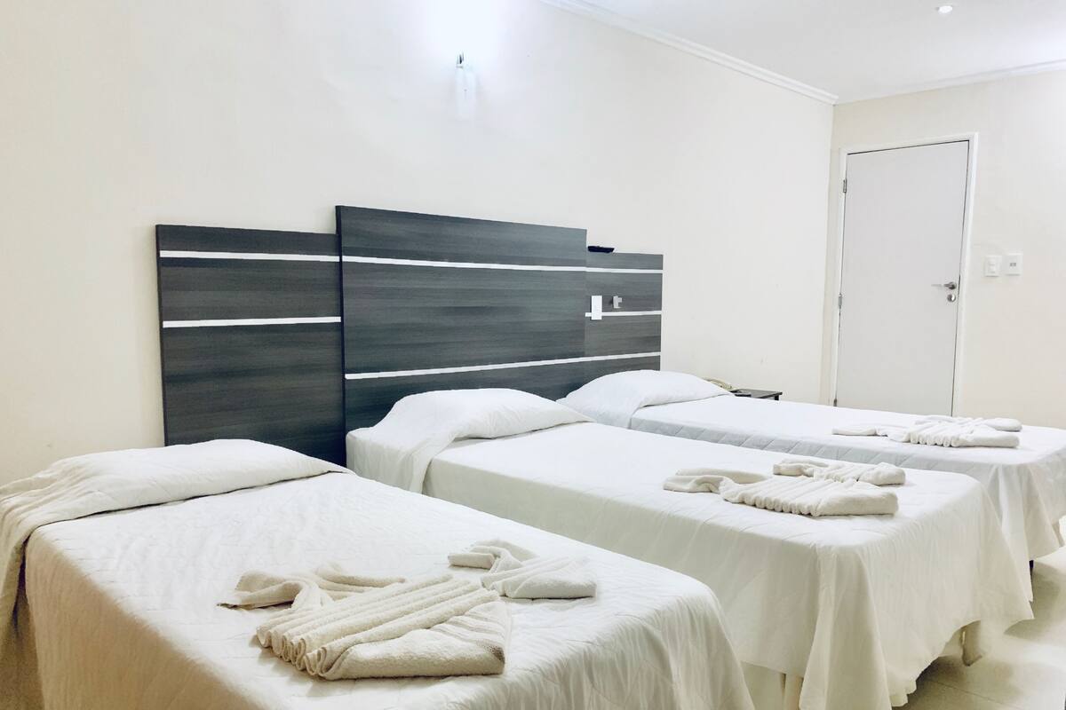 A hotel room with two single beds, each with a neatly folded towel.