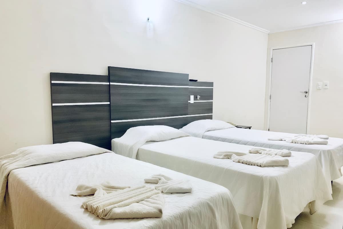 Habitación de hotel con dos camas individuales, cada una con una toalla doblada con cuidado.