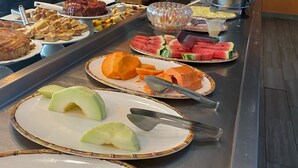 Una mesa de buffet con diferentes opciones de comida, como frutas, postres y bebidas.