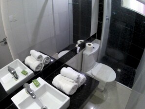 A bathroom with a sink, mirror, toilet, and a glass shower enclosure.