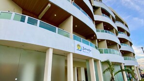 Un hotel de varios pisos con fachada curva, una palmera y un letrero que dice 'Beira Mar Hotel'.