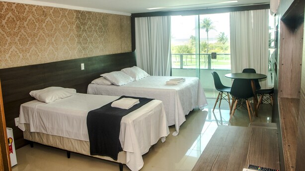 Habitación de hotel con dos camas, un comedor y vistas al exterior.