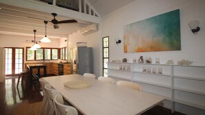 A spacious kitchen with wooden cabinets, a dining table with chairs, and a large painting on the wall.