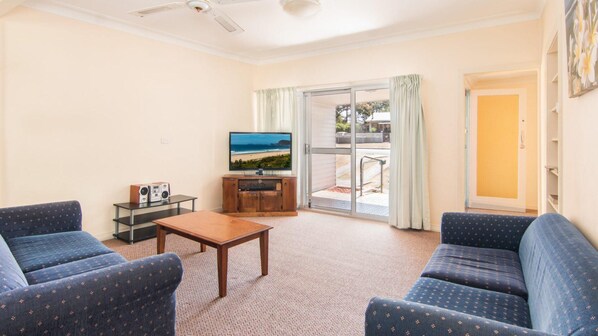 A living room with a television, a coffee table, and two blue patterned sofas.