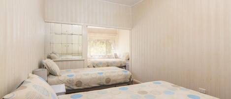 A room with two beds, a window, and a wardrobe.