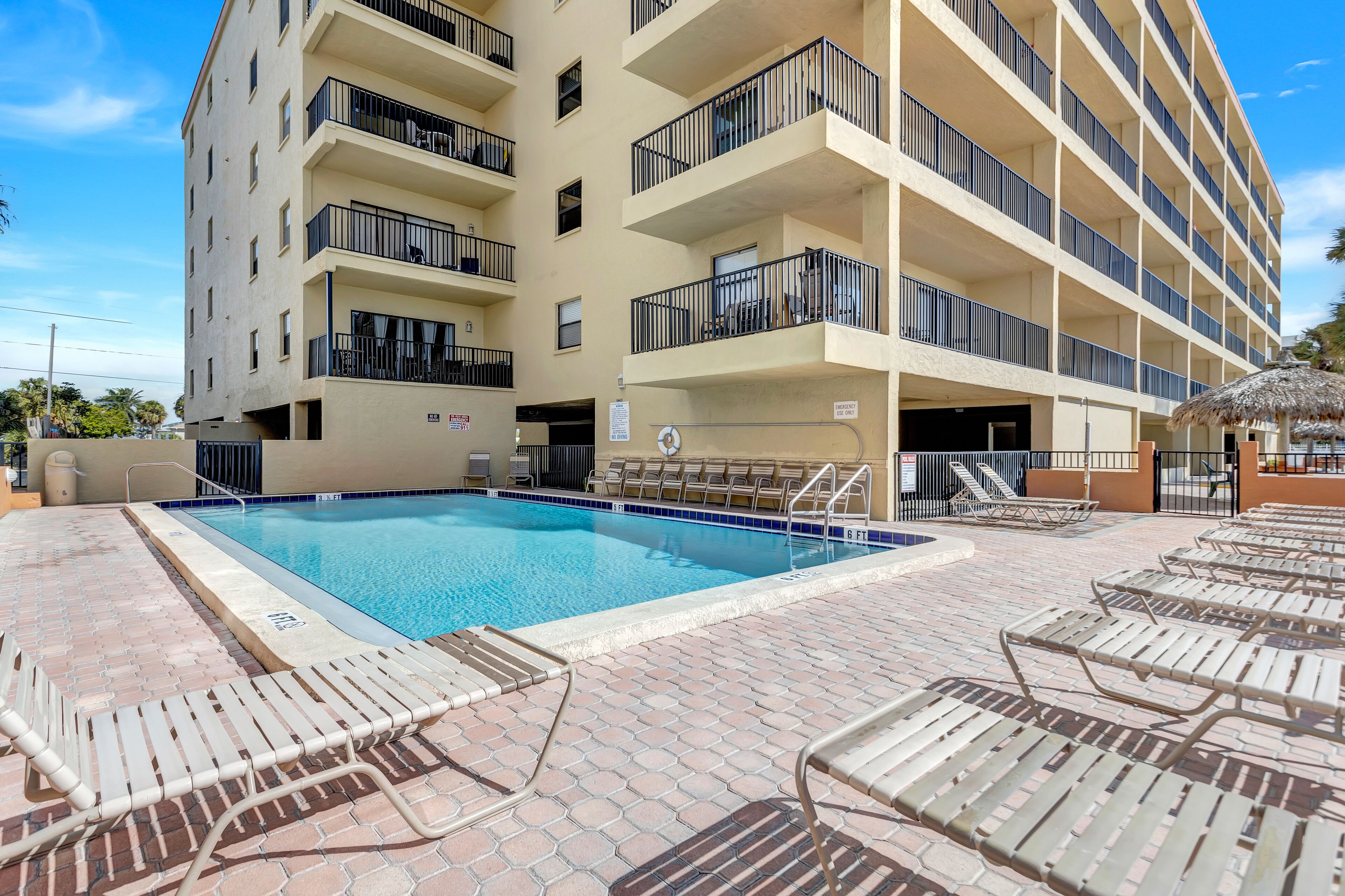 Ein Hotel mit Pool, Liegestühlen und einem mehrstöckigen Gebäude mit Balkonen.