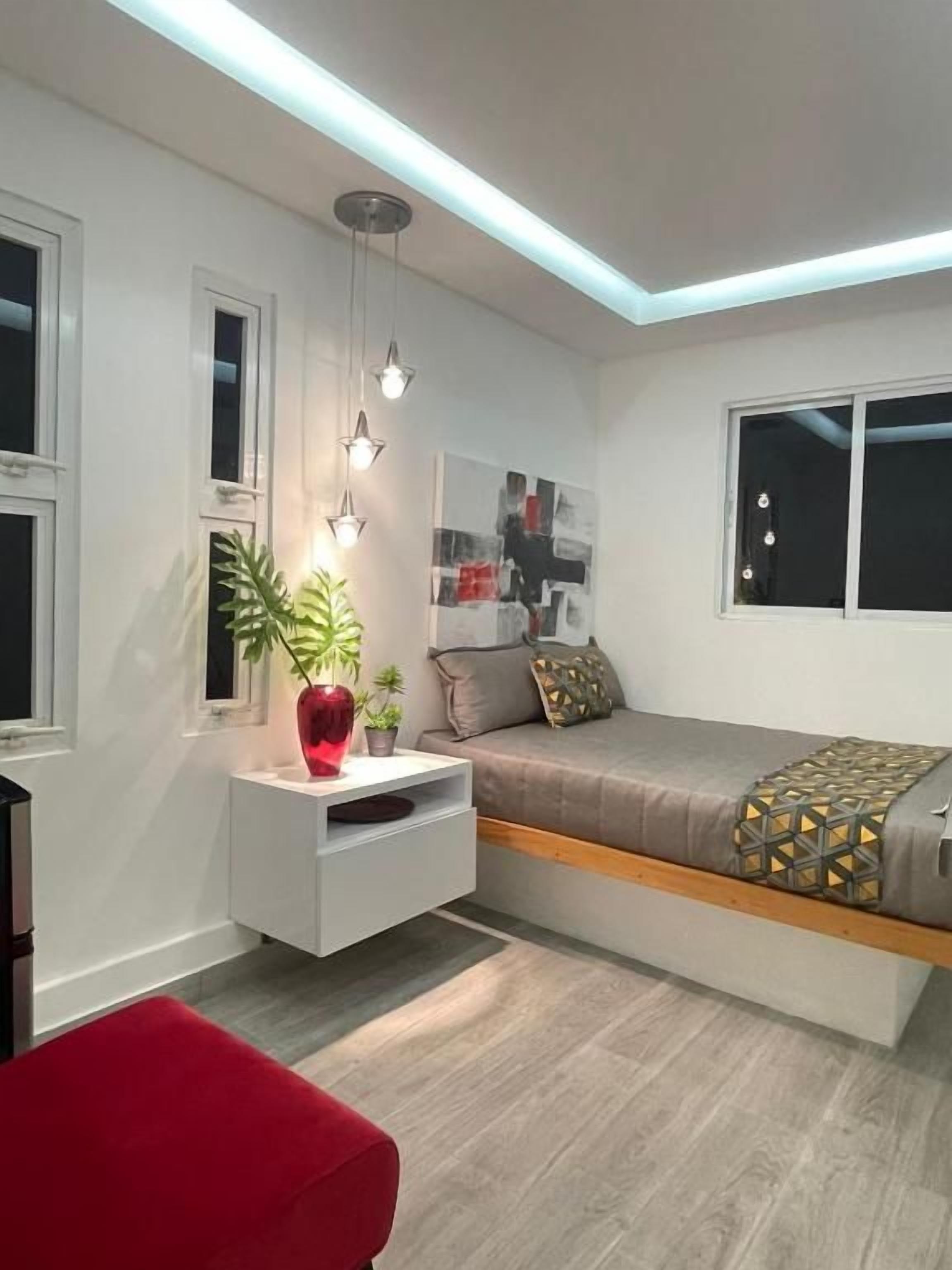 A modern bedroom with a bed, bedside table, and a red chair.