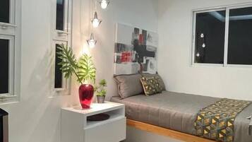 A modern bedroom with a bed, bedside table, and a red chair.