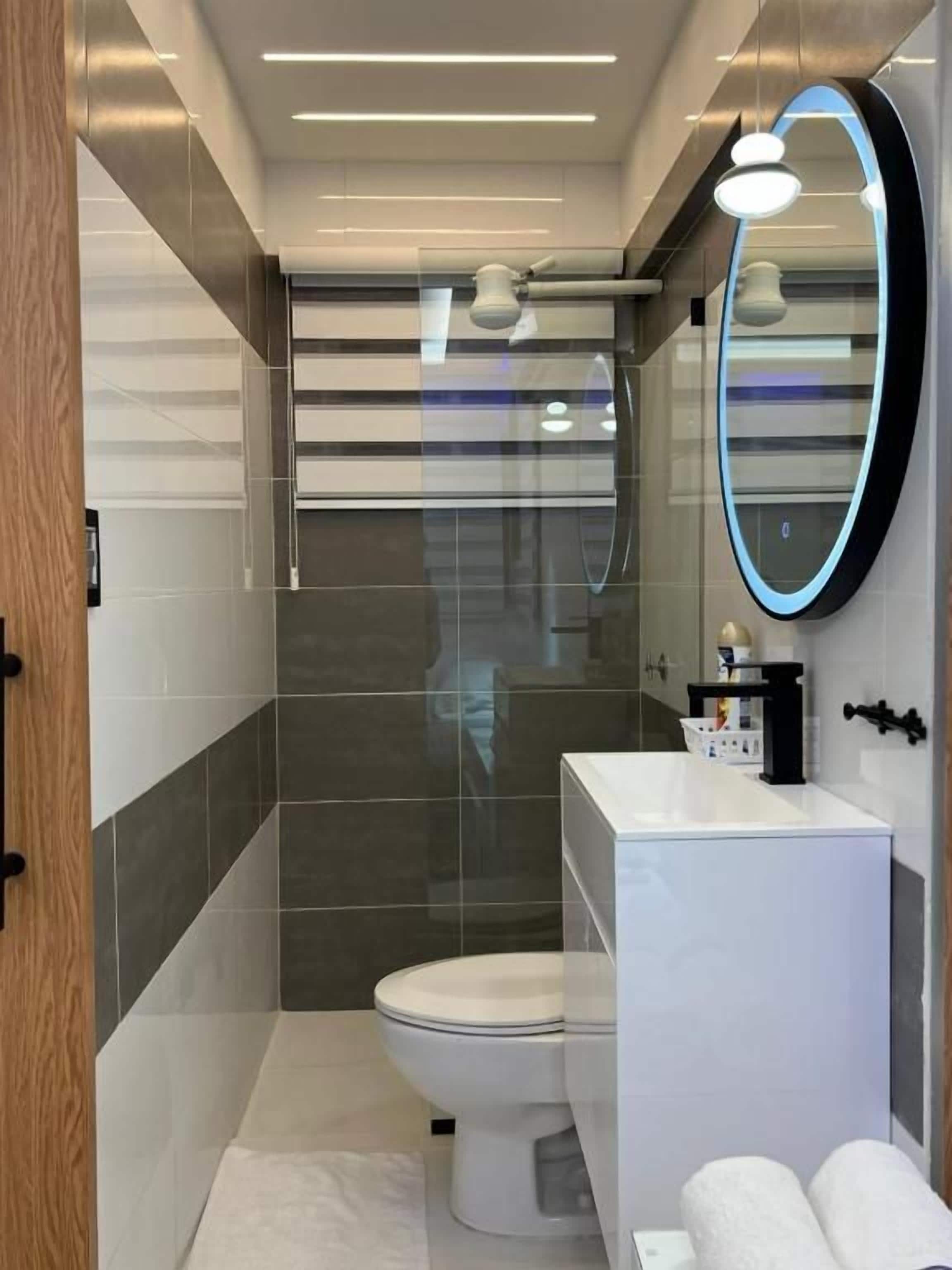 Ein modernes Badezimmer mit Toilette, Waschbecken und Spiegel.