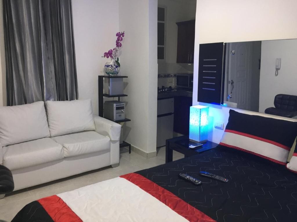 Une chambre d’hôtel avec un lit, un canapé, un bureau avec une lampe et une vue sur la cuisine.