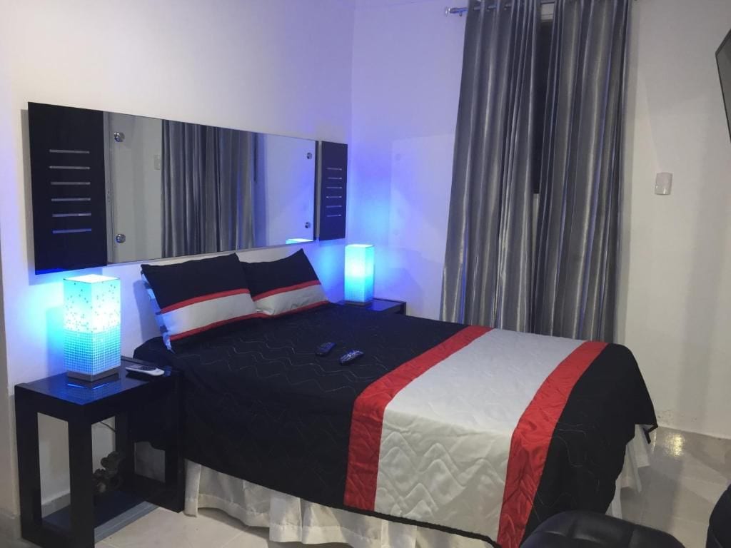 Una habitación de hotel moderna con una cama grande, mesitas de noche y un buró.