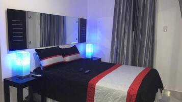 Una habitación de hotel moderna con una cama grande, mesitas de noche y un buró.