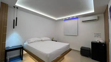 Un dormitorio moderno con una cama, una mesita de noche y aire acondicionado instalado en la pared.