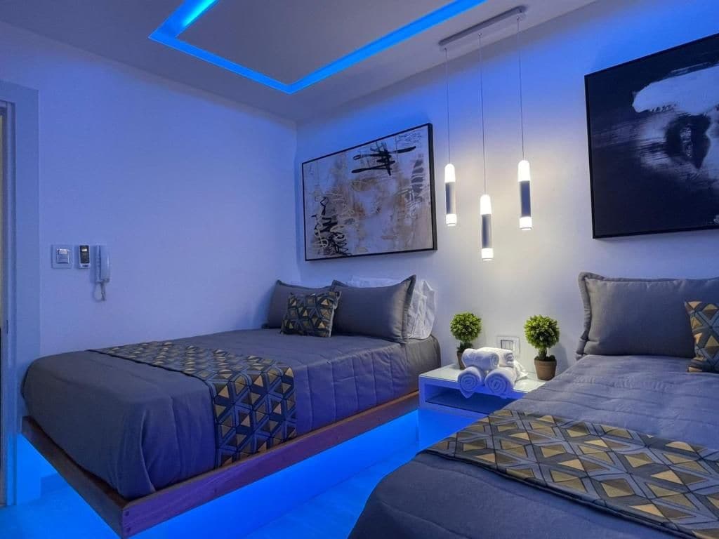 Ein modernes Hotelzimmer mit zwei Betten, einem Nachttisch mit Pflanze und Bildern an der Wand.