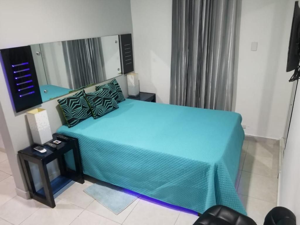 Une chambre à coucher avec un lit, une table de chevet, un miroir et un rideau.