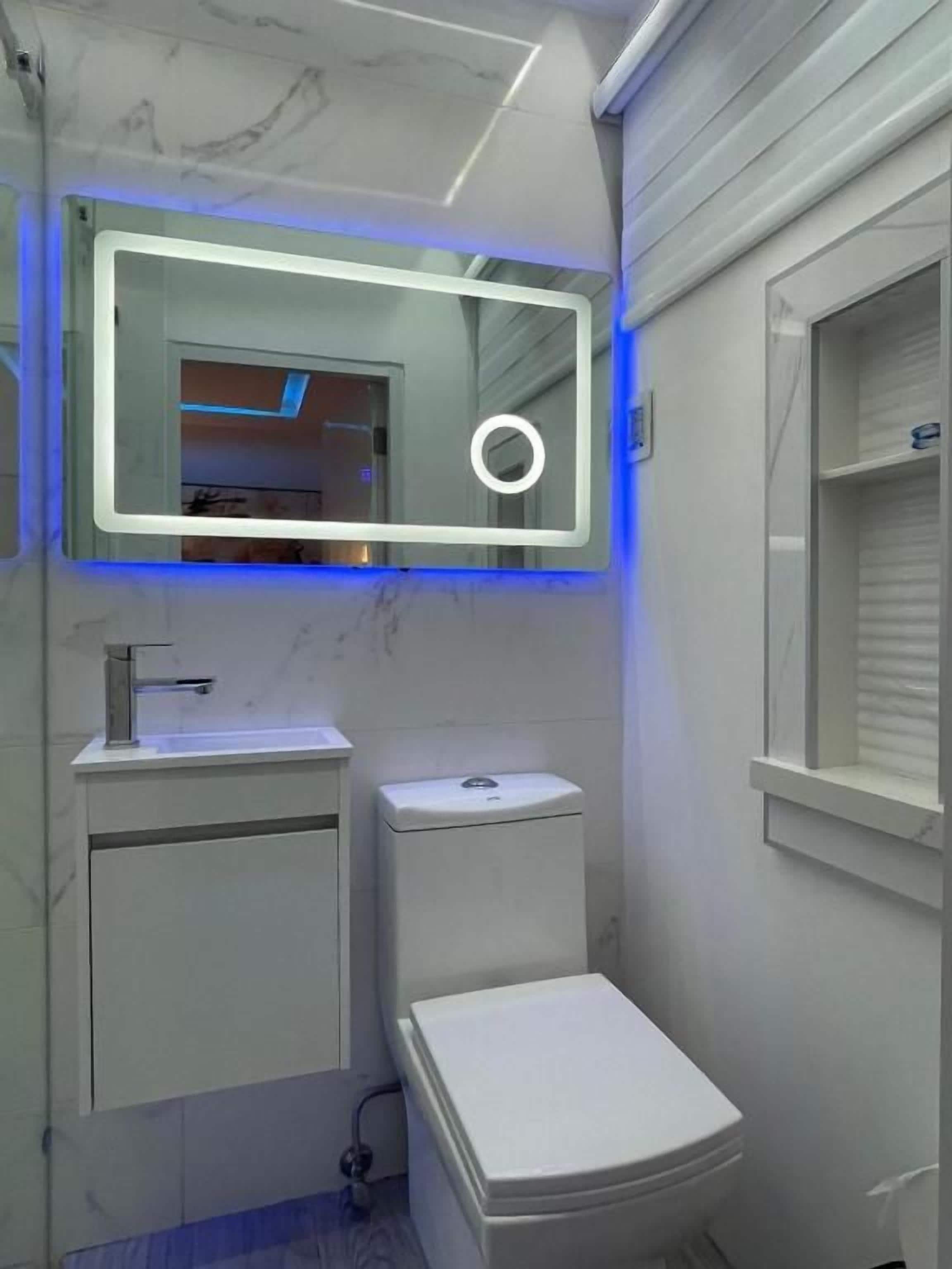 A bathroom with a toilet, sink, and mirror.