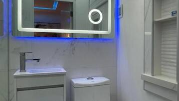 A bathroom with a toilet, sink, and mirror.