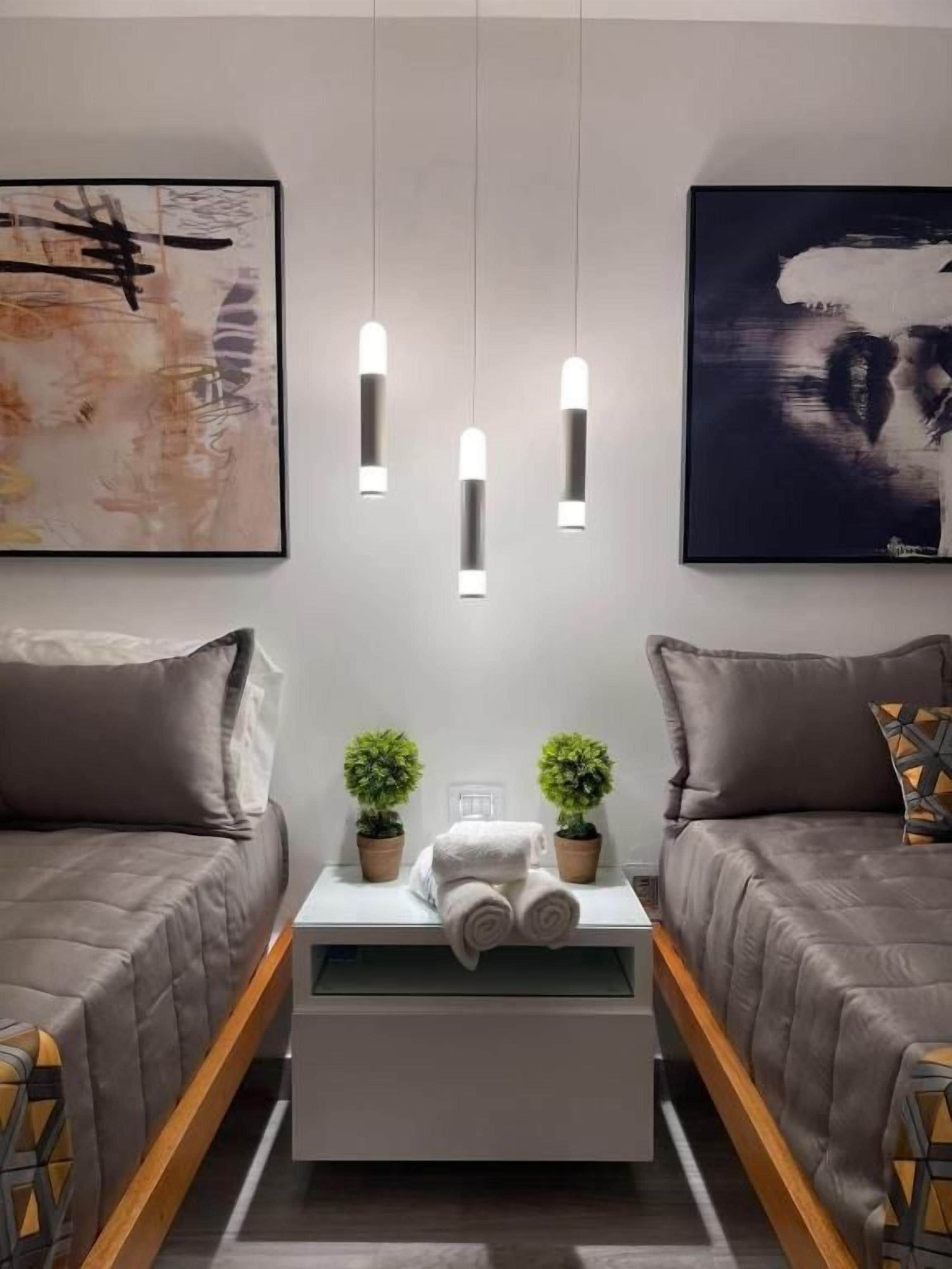 A modern bedroom with a bed, bedside tables, and artwork on the walls.