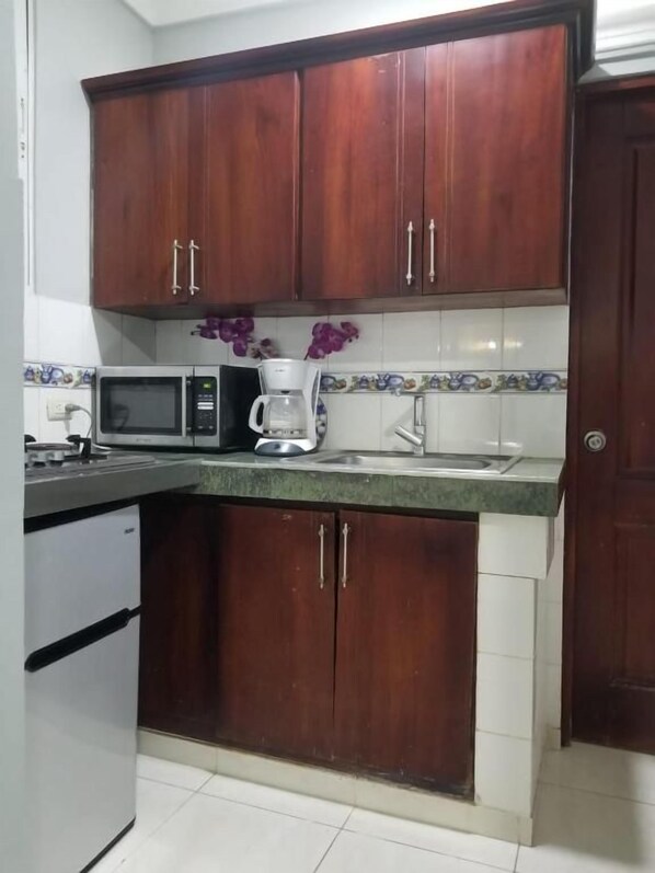 A kitchen with wooden cabinets, a microwave, a coffee maker, and a sink.