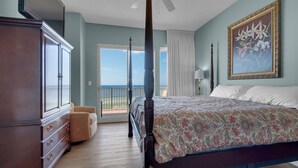 A bedroom with a four-poster bed, a large wardrobe, a chair, and a painting on the wall. - Treasure Island 0305 (Panama City Beach)