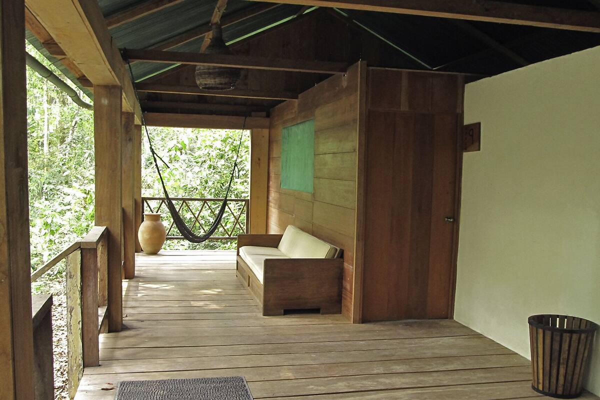 A wooden porch with a bench and a hanging hammock.
