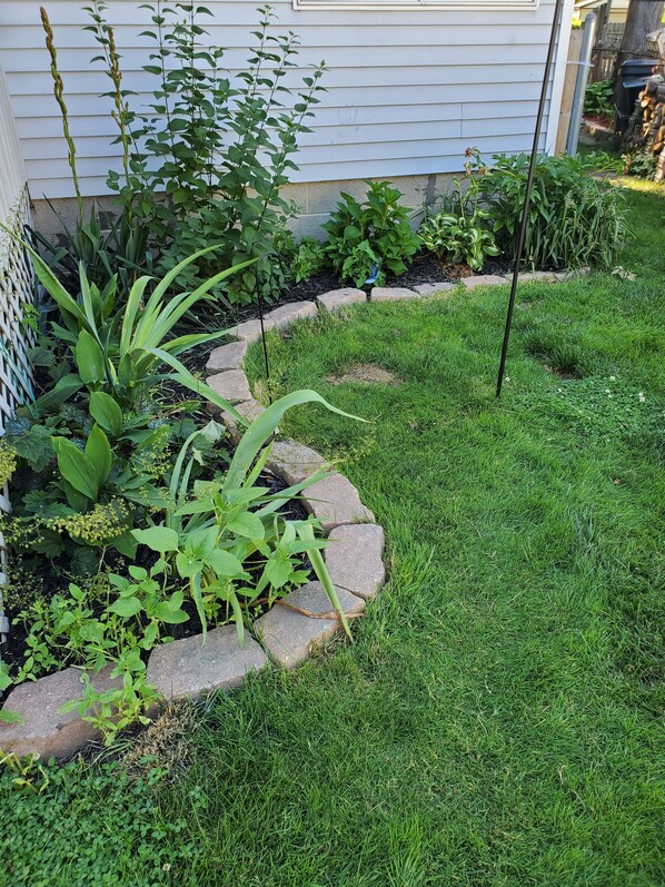 A garden with a variety of plants and a stone border. - Hampton House (Mount Clemens)