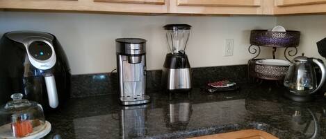 Een keuken met houten kastjes, een koffiezetapparaat, een blender, een waterkoker en een decoratief object op het aanrecht.