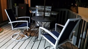 Un patio al aire libre con una parrilla, dos sillas y una mesa.