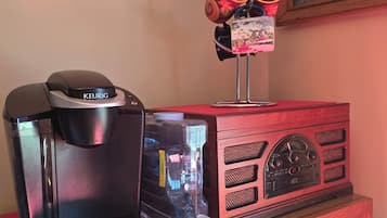 A coffee maker, a water dispenser, and a radio on a wooden cabinet.