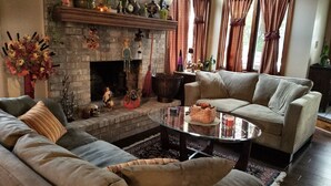 Una sala de estar acogedora con chimenea, un sofá, una mesa de centro y una ventana con cortinas.