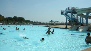 Una piscina con múltiples carriles, un tobogán de agua y una torre de salvavidas.