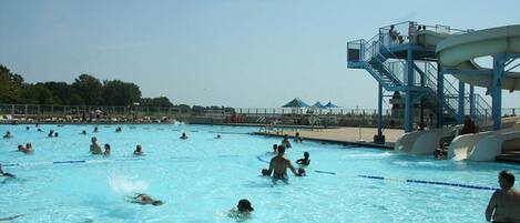 A swimming pool with multiple lanes, a water slide, and a lifeguard tower.