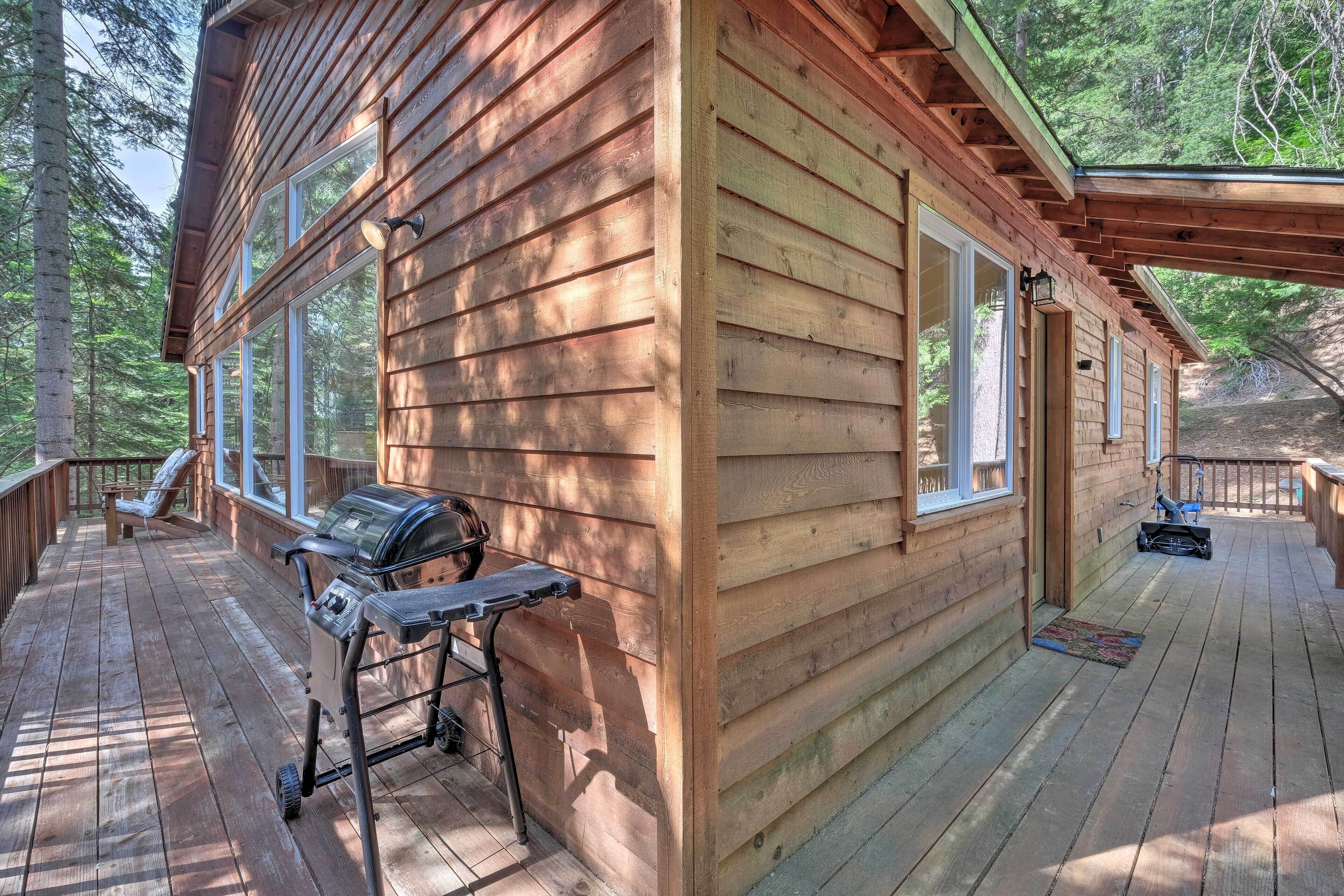 Eine Holzhütte mit einer Terrasse, einem Grill und einem überdachten Veranda-Bereich.