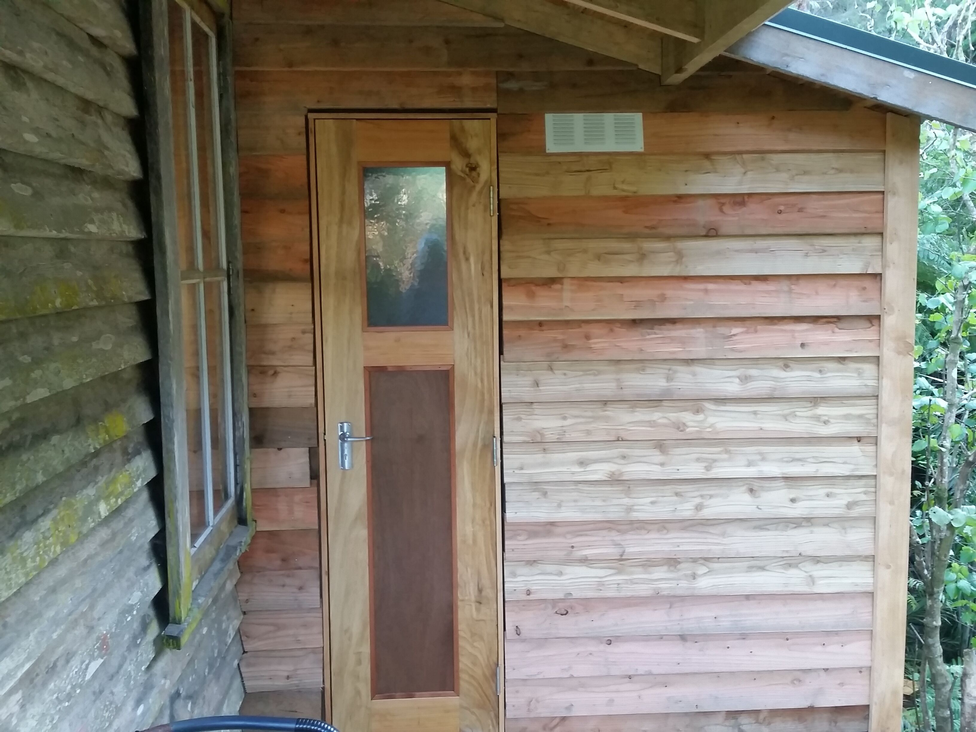 A wooden cabin with a glass door and a small window.