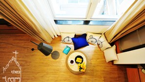 A cozy room with a wooden floor, a round table with a tray of food, a small lamp, and a window with curtains. - quiet, spacious and comfortable studio close to Hanoi Old Quarter (Dong Da)