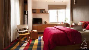 A bedroom with a bed, a desk, a chair, a TV, and a window with blinds. - quiet, spacious and comfortable studio close to Hanoi Old Quarter (Dong Da)