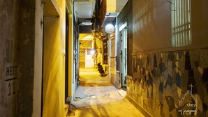 A narrow alleyway with a dog in the distance, stone walls, and a yellow door on the left. - quiet, spacious and comfortable studio close to Hanoi Old Quarter (Dong Da)